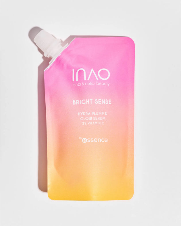 Ein farbenfroher Beutel mit der Aufschrift „INAO by essence Bright Sense Hydra Plump & Glow Serum Refill“ mit Hyaluronsäure weist einen Farbverlauf von Rosa nach Orange und einen weißen Deckel auf, der auf einem schlichten weißen Hintergrund abgesetzt ist.