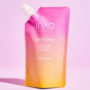 Auf einem rosa Hintergrund steht aufrecht ein rosa-gelber Farbverlaufsbeutel mit der Aufschrift „INAO by essence, Bright Sense Hydra Plump & Glow Serum Refill“ mit Hyaluronsäure.