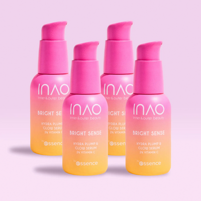 Vier Pumpflaschen mit rosa und gelben Farbverläufen des „Bright Sense Hydra Plump & Glow Serum“ von INAO by essence stehen auf einem hellrosa Hintergrund, am Boden jeder Flasche ist der Markenname angebracht.