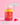 Eine Flasche INAO von Essence Clean Skin x JUICY BOMB Gummies steht auf einer rosa Oberfläche, daneben zwei herzförmige Gummibärchen. Textblasen sagen „Neues Design und neuer Geschmack“ und „Gleiche Formel. Mit Biotin & Zink, Vitamin C.“.