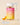 Eine Flasche INAO by essence Clean Skin Gummies mit einem rosa-orangefarbenen Etikett steht auf einem transparenten Block. Zwei Gummibärchen liegen daneben. Der Text hebt „Neues Design“ und „Gleiche Formel“ hervor.