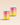 Zwei Flaschen INAO von essence Clean Skin Gummies mit rosa, orangefarbenen und gelben Farbverlaufsetiketten und weißen Deckeln. Die Etiketten betonen Ceramide und Vitamin-Komplex für ihre Schönheitsvorteile. Die Flaschen stehen vor einem neutralen beigen Hintergrund.