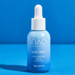 Eine Flasche Dewy Drop Deep Hydration Serum von INAO by essence mit blauem Farbverlauf und 2 % Hyaluron für tiefe Feuchtigkeitsversorgung sowie einem weißen Tropfverschluss steht auf einer blauen Fläche vor blauem Hintergrund.