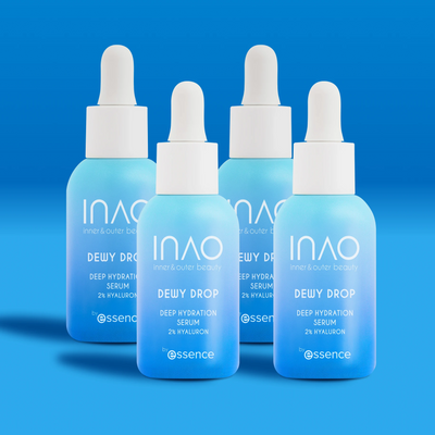 Vier blaue Flaschen INAO by essence Dewy Drop Deep Hydration Serum mit weißen Tropfern stehen vor blauem Hintergrund. Die Etiketten weisen 2% Hyaluronsäure für einen intensiven Feuchtigkeitsboost aus.