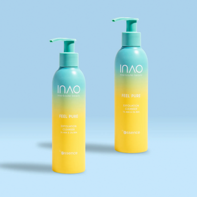 Zwei Flaschen INAO by essence Feel Pure AHA & BHA Exfoliation Cleanser mit blaugrüner Pumpe und gelbem Farbverlaufsdesign stehen auf einer hellblauen Oberfläche vor einem dazu passenden blauen Hintergrund.