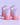 Auf einem hellvioletten Hintergrund sind vier „INAO by essence Fine Time Pore Minimizer Serum Refill“-Beutel in Rosa und Lila mit weißem Verschluss abgebildet – ideal für unreine Haut.