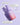 Eine Flasche INAO by essence Fine Time Pore Minimizer Serum Packs liegt auf einer violetten Oberfläche mit Reflexen und einem Text, der die veganen und Akne behandelnden Eigenschaften hervorhebt.