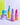Farbenfrohe Hautpflege-Serumpackungen „Fine Time Pore Minimizer Serum Packs“ von INAO von der Marke essence, präsentiert vor einem leuchtend gelben und grünen Hintergrund. Die Artikel umfassen Cremes und Gesichtsserum in rosa, violetten und blauen Behältern.