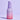 Eine Flasche INAO by essence Fine Time Pore Minimizer Serum mit 10 % Azelainsäure für unreine Haut in Lila und Rosa mit Farbverlauf ist auf einem hellvioletten Hintergrund zu sehen, auf dem Pumpspender ist das Logo von essence zu sehen.