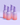 Vier rosa und violette Flaschen des Fine Time Pore Minimizer Serums von INAO by essence für unreine Haut sind auf einem hellvioletten Hintergrund mit Farbverlauf angeordnet.