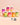 Sieben bunte Flaschen INAO by essence Hair YEAH! Gummies – jede mit Inhaltsstoffen wie Zink, Biotin oder Selen für verschiedene gesundheitliche Vorteile – sind auf einem pfirsichfarbenen Hintergrund angeordnet. Unter den Flaschen sind Vegan- und Halal-Symbole abgebildet.