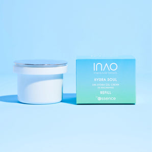 Ein weißer Tiegel mit der Hydra Soul 24h Hydra Gel Cream Refill von INAO by essence mit silbernem Deckel steht neben einer hellblauen Box. Beide bieten intensive Feuchtigkeitsversorgung vor einem passenden hellblauen Hintergrund.