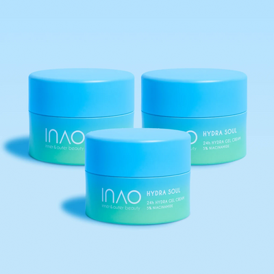 Drei blaue Tiegel mit der 24-Stunden-Hydra-Gel-Creme „Hydra Soul 24h“ von INAO by essence mit 5 % Niacinamid stehen mit passenden Deckeln auf einer blauen Fläche, werfen sanfte Schatten und spenden 24 Stunden lang Feuchtigkeit.