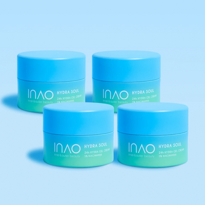 Vier blaue Tiegel mit der 24-Stunden-Hydra-Gel-Creme „Hydra Soul 24h“ von INAO by essence mit 3 % Niacinamid sind auf einer blauen Fläche und einem Hintergrund mit Farbverlauf angeordnet und betonen die intensive 24-Stunden-Feuchtigkeitsversorgung.