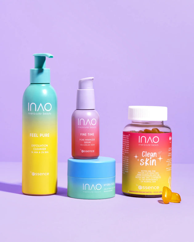 Vier farbenfrohe Hautpflege- und Nahrungsergänzungsprodukte von INAO by essence Slay More Sparset werden in leuchtend gelben, rosa und blauen Verpackungen auf einer violetten Oberfläche mit passendem violetten Hintergrund präsentiert.
