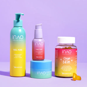 Vier farbenfrohe Hautpflege- und Nahrungsergänzungsprodukte von INAO by essence Slay More Sparset werden in leuchtend gelben, rosa und blauen Verpackungen auf einer violetten Oberfläche mit passendem violetten Hintergrund präsentiert.
