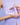 Eine Person hält eine kleine, violette INAO-Hautpflegeflasche von essence mit der Aufschrift „Routine Imperfections“ in den Händen und trägt dazu ein passendes violettes strukturiertes Hemd. Das Bild zeigt pastellfarbene Nägel und den Text „Step 2 Treat“.