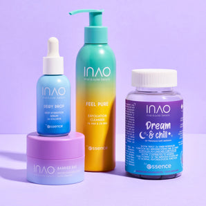 Vier farbenfrohe INAO by essence Dreamy Skin Sparset-Produkte sind auf einer violetten Oberfläche und einem violetten Hintergrund angeordnet und umfassen eine Tropfflasche, eine Pumpflasche, ein Glas und „Dream & Chill“-Gummis – ideal für Ihre entspannende Hautpflegeroutine vor dem Schlafengehen.