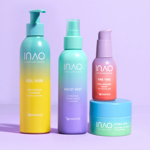 Vier farbenfrohe INAO by essence Anti-Unreinheiten mit INAO-Produkten – Feel Pure, Moist Mist, Fine Time und Hydra Soul – sind auf einer violetten Fläche mit lavendelfarbenem Hintergrund arrangiert. Das Display enthält sowohl Flaschen als auch einen Tiegel.