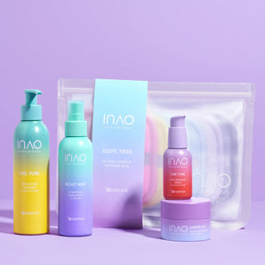 Vier farbenfrohe INAO by essence Happy Evenings Sparset-Pflegeprodukte und ein transparenter Reißverschlussbeutel werden auf violettem Hintergrund präsentiert. Das Set enthält Flaschen, einen Tiegel und wiederverwendbare Make-up-Entferner-Pads in Pastellfarben.