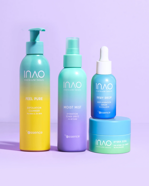 Vier farbenfrohe INAO by essence Happy Moisture Sparset-Produkte – Peeling-Reiniger, Toner-Spray, Serum und Gel-Creme – liegen auf einer violetten Oberfläche. Ihre Verpackung in den Farbverläufen Blau, Grün und Gelb betont die intensive Feuchtigkeitsversorgung.