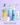 Vier INAO by essence Happy Moisture Sparset-Produkte in bunten Flaschen stehen auf einer pastellfarbenen Oberfläche, wobei deutscher Text Eigenschaften wie „Hydration mit Toner“, „Exfoliation Cleanser“ und „24h Feuchtigkeit mit Niacinamide“ hervorhebt.