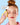 Eine Frau mit roten Haaren und rosa Lidschatten wischt sich mit einem gelben Swipe Tribe Reusable Makeup Remover Pad von INAO by essence über die geschlossenen Augen. In einer Sprechblase steht auf hellblauem Hintergrund: „Entfernt selbst wasserfestes Make-up …“.