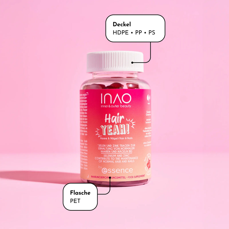 Eine rosa Plastikflasche mit der Aufschrift „INAO Hair Yeah!“ und weißem Deckel steht auf einem rosa Untergrund. Textfelder weisen darauf hin, dass der Deckel aus HDPE, PP und PS und die Flasche aus PET besteht. Das Etikett enthält Marken- und Produktdetails.