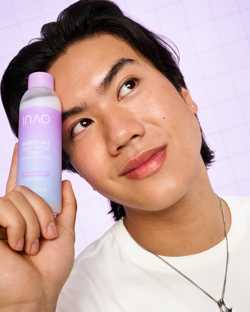 Lächelnde Person hält die Flasche des Barrier Bae Milky Peptide Toner an die Stirn.