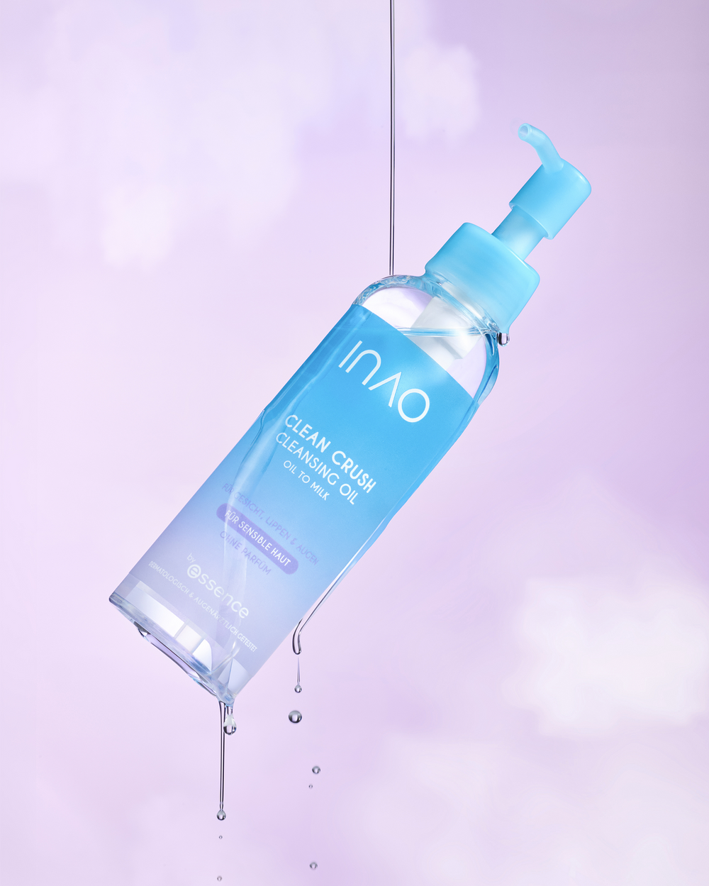 Das Clean Crush Cleansing Oil schwebt vor lila Hintergrund, während Öl aus der Pumpe tropft.