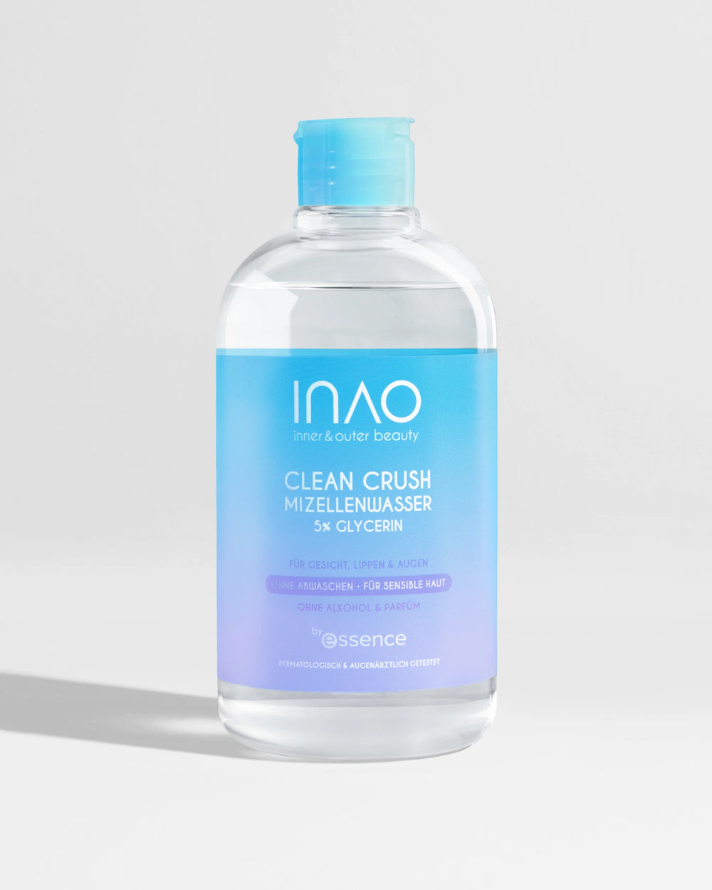 Eine durchsichtige Kunststoffflasche mit einem blau-lila Etikett mit der Aufschrift "Clean Crush Mizellenwasser" von INAO by essence steht aufrecht auf einer hellgrauen Fläche vor einem weißen Hintergrund.