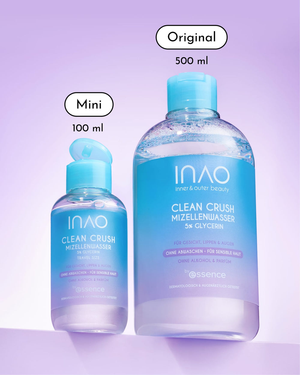Zu sehen sind zwei Flaschen „INAO Clean Crush Mizellenwasser“: links die Reisegröße (100 ml) und rechts die Originalflasche (500 ml), beide mit blauer Flüssigkeit und hellblauen Verschlüssen vor einem violetten Hintergrund. Dieser milde Make-up-Entferner von INAO ist ideal für empfindliche Haut und sorgt jedes Mal für eine sanfte und dennoch wirksame Reinigung.