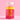Eine durchsichtige Plastikflasche mit der Aufschrift „Clean Skin x JUICY BOMB Gummies“ von INAO by essence, gefüllt mit leuchtend rosa Gummibärchen, reich an Biotin und Zink, steht auf einer rosa Fläche mit rosa Hintergrund. Das Etikett hat gelb-rosa Text und einen weißen Verschluss.