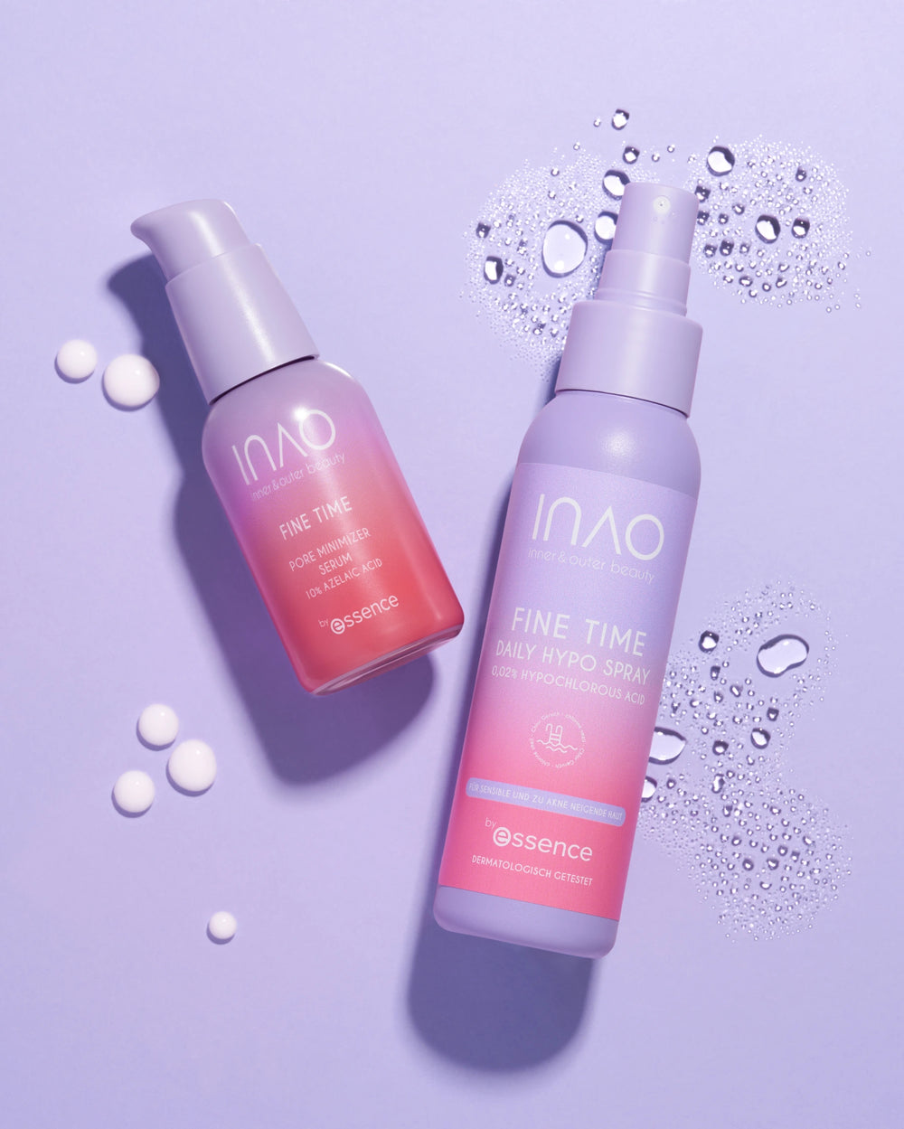 Zwei INAO by essence Fine Time Daily Hypo Spray Flaschen, eine rosa und eine lila, liegen auf einer lavendelfarbenen Fläche mit Wassertropfen und Cremeschmierern, die die Produkte Daily Hypo Spray und Pore Minimizer hervorheben.