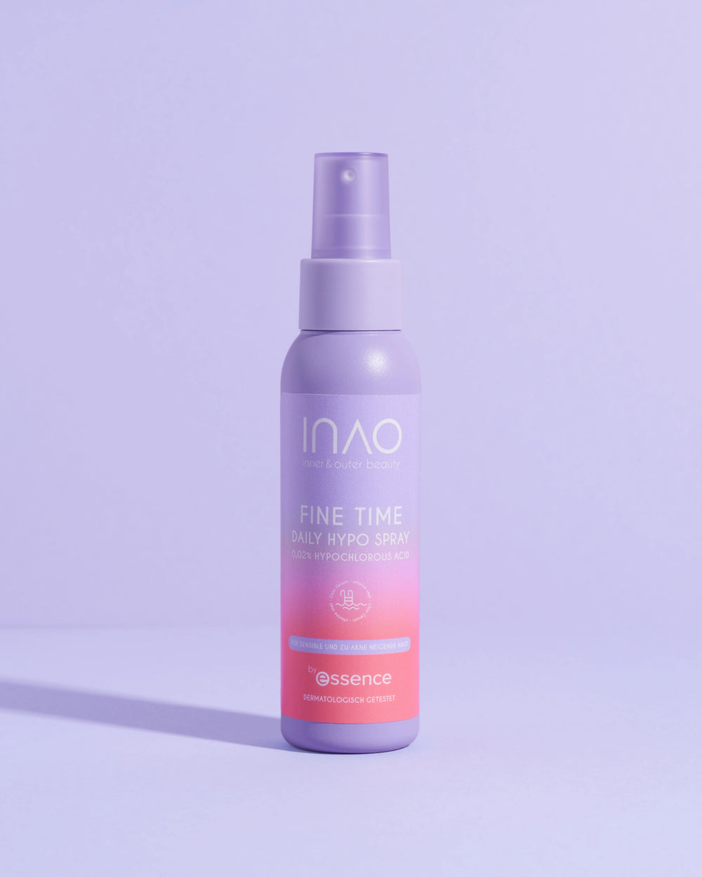Eine violette Flasche Fine Time Daily Hypo Spray von INAO by essence (0,025% hypochlorige Säure) steht aufrecht auf einer violetten Fläche und wirft einen Schatten auf einen hellvioletten Hintergrund.