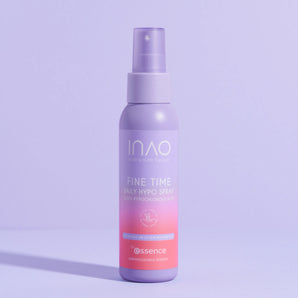 Eine violette Flasche Fine Time Daily Hypo Spray von INAO by essence (0,025% hypochlorige Säure) steht aufrecht auf einer violetten Fläche und wirft einen Schatten auf einen hellvioletten Hintergrund.
