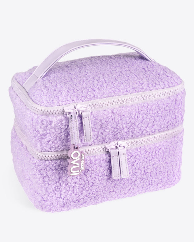 Eine weiche, lavendelfarbene INAO „Fluffy Mood“-Kosmetiktasche mit Sherpa-Struktur, doppelter Lagenausführung, zwei Fächern mit Reißverschluss, einem passenden Tragegriff und einem „INAO“-Reißverschlusszug – perfekt als stilvoller Reisebegleiter zum Aufbewahren von Make-up.