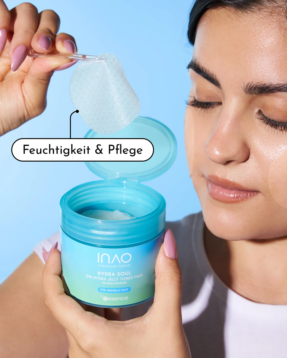 Eine Frau mit strahlender Haut hält ein strukturiertes Jelly Toner Pad über einem geöffneten türkisfarbenen Tiegel mit der Aufschrift "INAO by essence Hydra Soul 24h Hydra Jelly Toner Pads". Der Text "Feuchtigkeit & Pflege" hebt die mit Niacinamid angereicherte Formel hervor.