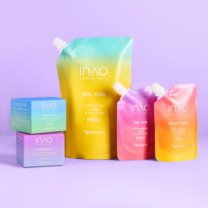 Die Nachfüllpackungen und Boxen für die Hautpflegeprodukte „Refill Lover“ von INAO by essence sind auf einer hellvioletten Oberfläche angeordnet und bieten mit ihren Pastellverläufen in Gelb, Blau, Rosa und Lila nachhaltige Nachfülloptionen.