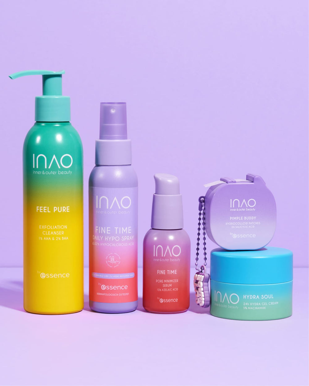 Fünf leuchtende INAO by essence Anti-Unreinheiten Sparset Produkte, darunter Seren und Reiniger in bunten Flaschen und einem runden Behälter, sind auf einer violetten Fläche mit passendem Hintergrund angeordnet, um Unreinheiten zu bekämpfen.