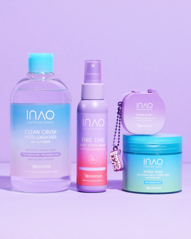 Auf einem violetten Hintergrund sind vier INAO by essence New Drop Sparset Hautpflegeprodukte aufgereiht - Micellarwasser für sanfte Reinigung, Spray, Creme und ein runder Behälter - alle in pastellblauen, violetten und grünen Verpackungen.