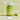 Eine grüne Flasche mit der Aufschrift „Immune Tune“ von INAO steht vor einem hellgelben Hintergrund, daneben liegen zwei grüne Gummibärchen. Der Text hebt die Vitamine, Mineralien und den Limettengeschmack hervor und weist darauf hin, dass das Produkt vegan, glutenfrei und laktosefrei ist.