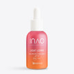 Eine Glasflasche mit einem Farbverlauf von Rosa bis Orange und der Aufschrift „Light Lover High Protection Serum SPF 50“ von INAO by essence mit weißem Tropfverschluss steht aufrecht auf einem schlichten weißen Hintergrund und sorgt mit LSF 50 für einen natürlichen Glanz.