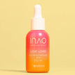 Eine Flasche INAO by essence Light Lover High Protection Serum SPF 50 mit Farbverlauf in Rosa und Orange und einer weißen Tropfkappe steht aufrecht vor einem einfarbig gelben Hintergrund – ideal für einen natürlichen Glanz.
