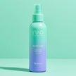 Ein blaugrüner und lavendelfarbener INAO von essence Moist Mist Hydration Toner Spritz steht aufrecht auf einer pastellfarbenen Oberfläche und hebt die feuchtigkeitsspendende Kraft von Betain vor einem minimalistischen Hintergrund in Blaugrün und Mintgrün hervor.