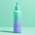 Ein blaugrüner und lavendelfarbener INAO von essence Moist Mist Hydration Toner Spritz steht aufrecht auf einer pastellfarbenen Oberfläche und hebt die feuchtigkeitsspendende Kraft von Betain vor einem minimalistischen Hintergrund in Blaugrün und Mintgrün hervor.