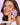 Eine lächelnde Frau mit reiner Haut hält eine violette Schachtel mit INAO Pimple Buddy Hydrokolloid-Pflastern – Cloud Edition – in der Hand. Sie hat kleine rosa Pickel im Gesicht. Ein deutscher Text in der unteren linken Ecke hebt die Wirksamkeit des Produkts hervor.