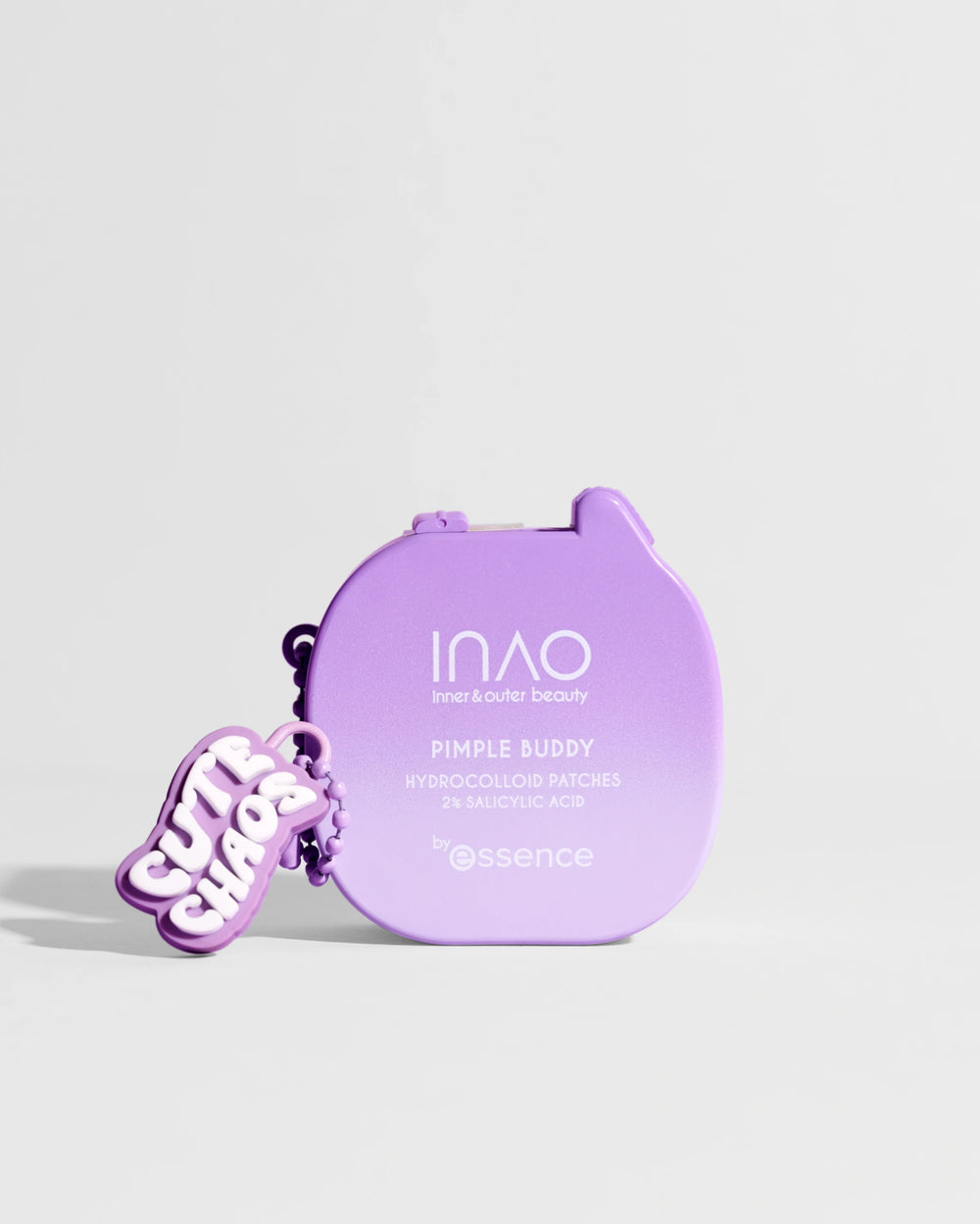 Ein kleiner violetter Behälter mit der Aufschrift "Pimple Buddy Hydrocolloid Patches" von INAO by essence, an dem ein "CUTE SHOOK"-Schlüsselanhänger befestigt ist, vor einem schlichten hellen Hintergrund.