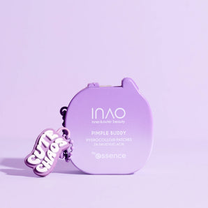 Ein lavendelfarbener Behälter mit der Aufschrift "Pimple Buddy Hydrocolloid Patches" von INAO by essence steht auf einer pastellfarbenen lila Fläche, die mit einem "Cute Chaos"-Schlüsselanhänger geschmückt ist, und das alles in einem zart lila gehaltenen Rahmen.